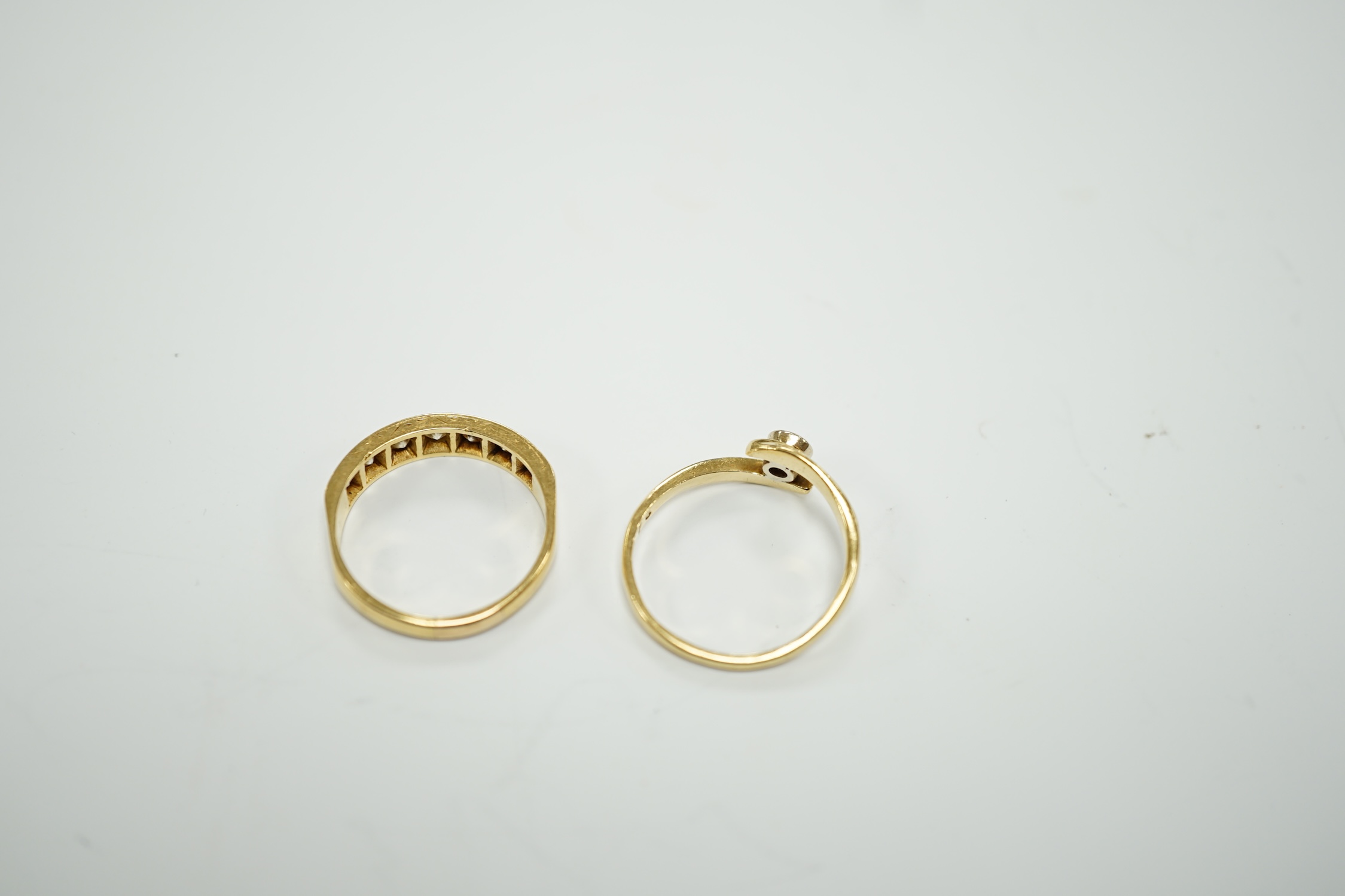 A modern 18ct gold and graduated seven stone diamond set half hoop ring, size O and a similar solitaire diamond ring with crossover setting, gross weight 6.4 grams.